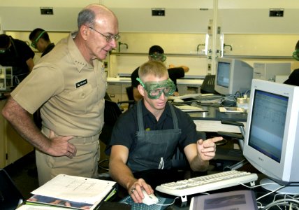 US Navy 040903-N-5390M-004 Chief of Naval Operations (CNO), Adm. Vern Clark, looks on as Midshipmen 4th Class Daniel Walker explains his most recent lab work