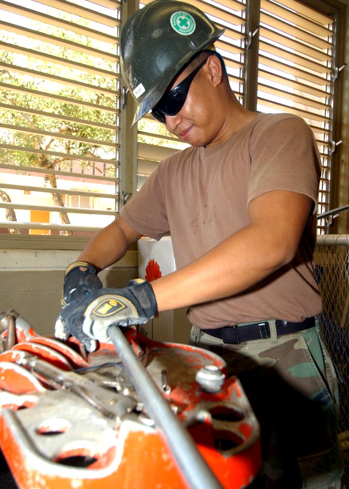 US Navy 040927-N-3019M-002 Engineering Aide 2nd Class Richard Vilar, assigned to Naval Construction Battalion Unit Four One Three (CBU-413), cuts electrical piping for a new wall