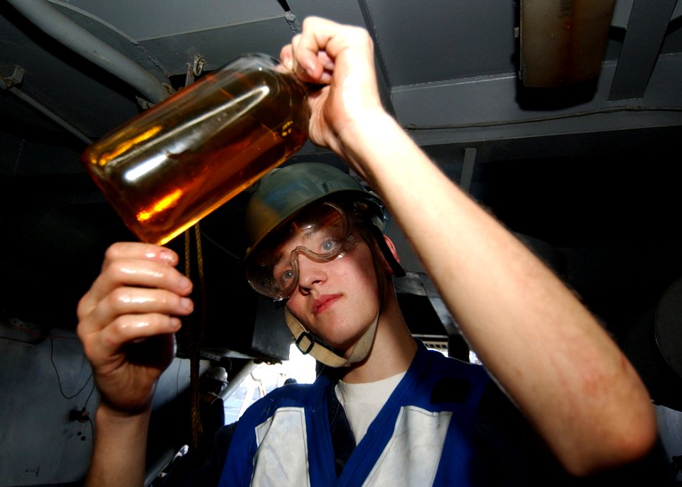 US Navy 040917-N-4374S-006 Machinist Mate 3rd Class Mathew Jensen assigned to the aircraft carrier USS John F. Kennedy (CV 67) views a sample of fuel during an underway replenishment