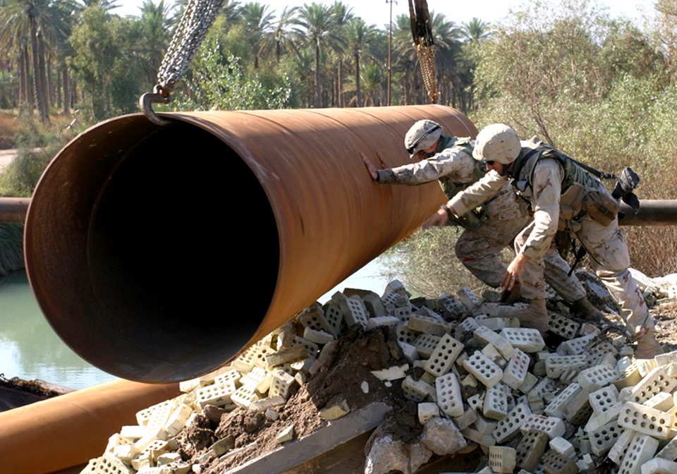 US Navy 041113-B-1250B-003 A Sailor and Marine assigned to the 24th Marine Expeditionary Unit (24th MEU) guide a pipe into a river in Lutafiyah, Iraq
