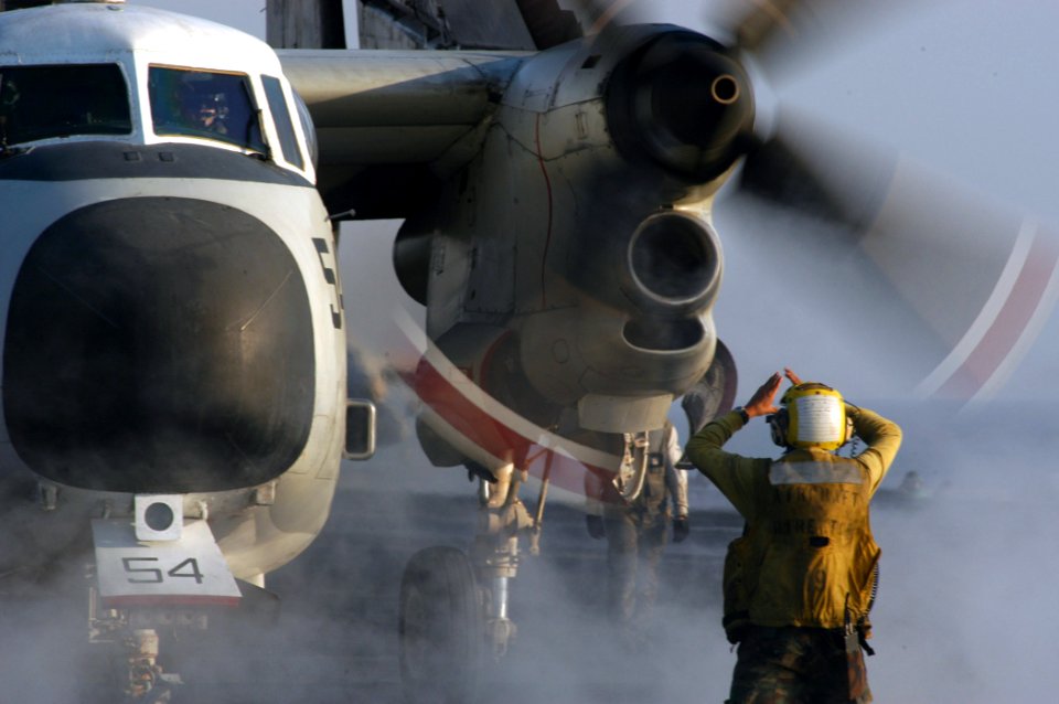 US Navy 040923-N-8704K-004 An Aviation Boatswain's Mate signals for a C-2A Greyhound to speed up the propeller rotation prior to launch aboard the conventionally powered aircraft carrier USS John F. Kennedy (CV 67)