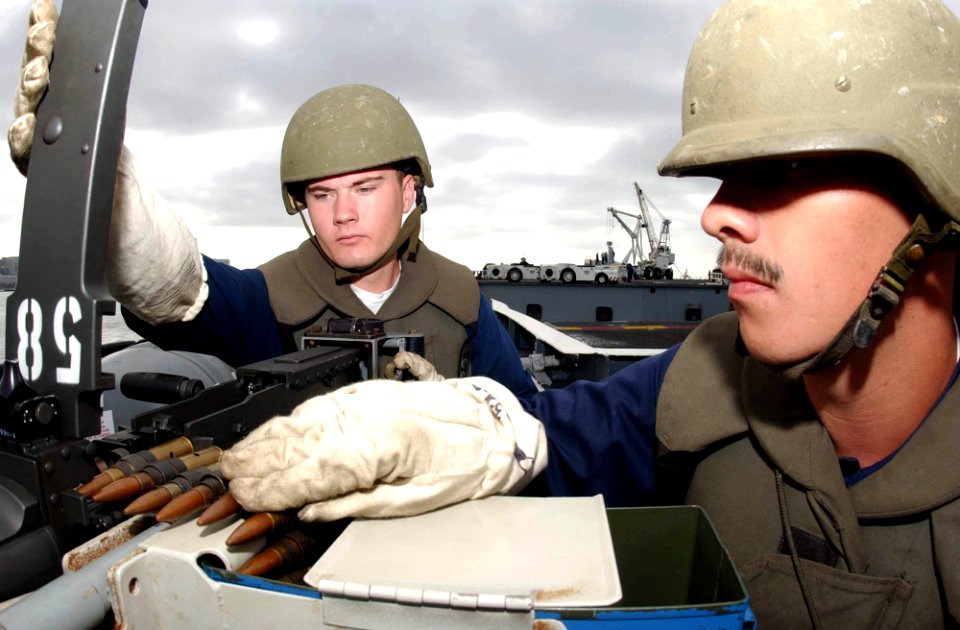 US Navy 040928-N-8158F-133 Aviation Ordnanceman 3rd Class Charles Wilker of Fowler, Calif., left and Aviation Ordnanceman 3rd Class Allen Ortega of Winnemucca, Nev., practice loading drills on a .50 caliber machine gun