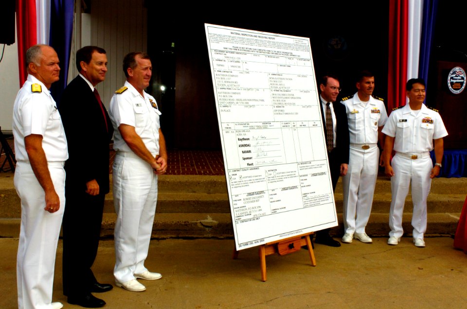 US Navy 040929-N-0295M-006 Official party members pose after signing a large DD250 transfer form as the U.S. Navy formally welcomes Raytheon Company's Tomahawk Block IV cruise missile into the Navy's arsenal