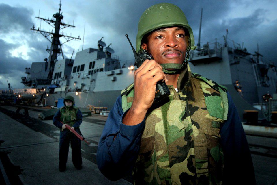 US Navy 041028-N-3228G-003 Gas Turbine System Mechanical 1st Class Pierre Brewster assigned to the Arleigh Burke-class guided missile destroyer USS Chafee (DDG 90), watches a group of simulated demonstrators