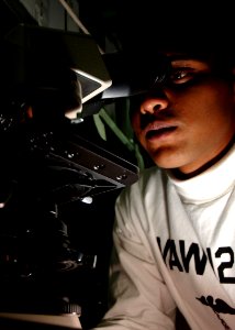 US Navy 041022-N-5345W-020 Hospital Corpsman Jay Amin assigned to the Seahawks of Carrier Airborne Early Warning Squadron One Two Six (VAW-126), examines medical slides, under a microscope, during sick call