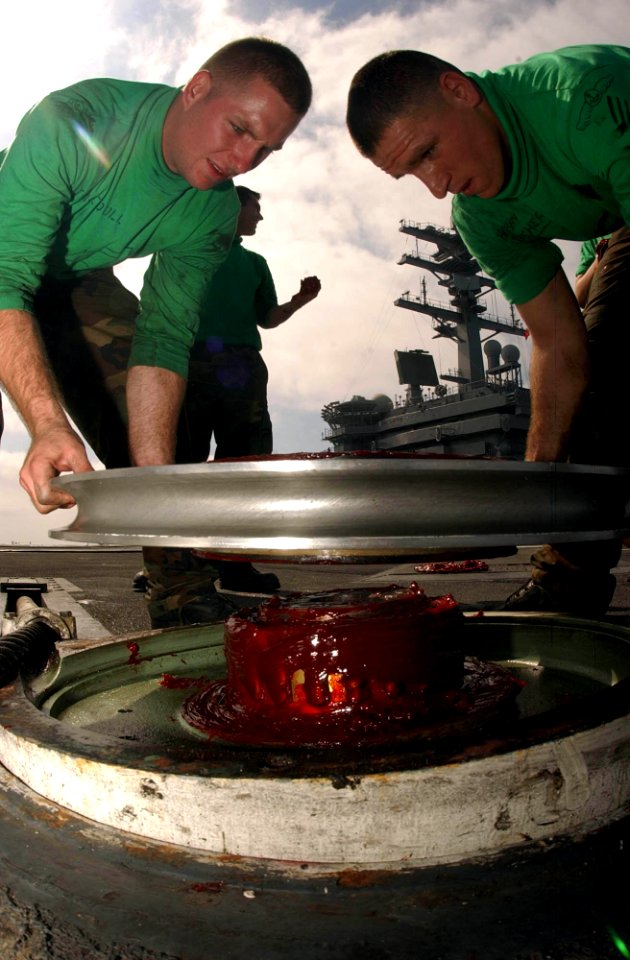 US Navy 041006-N-8158F-225 Airman Andy Boucher of Hulbert, Okla., right, and Airman Mike Kirkendoll of San Diego, Calif., resets topside retractable sheaves during routine maintenance on flight deck aboard the aircraft carrier
