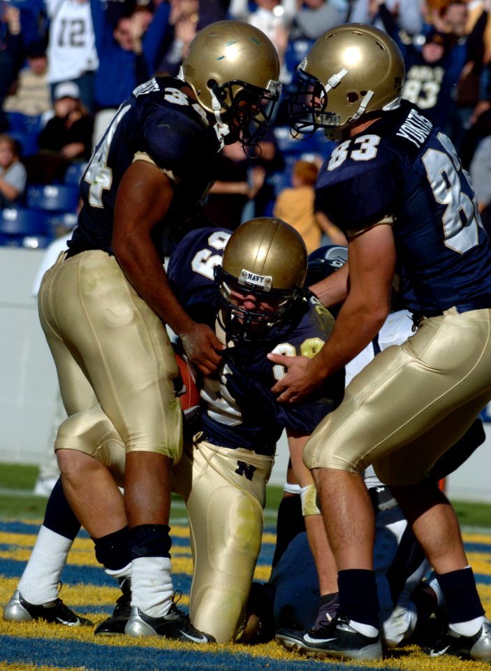 US Navy 041023-N-9693M-011 U.S. Naval Academy Midshipman 1st Class Eric Roberts, left, and Midshipman 2nd Class Mick Yokitis, right, congratulate Midshipman 1st Class Corey Dryden on a recovered fumble in the end zone