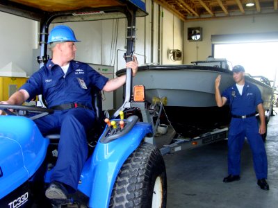 US Navy 040903-N-0000W-001 Boatswain's Mate 2nd Class Kristoffer Post, foreground, takes directions from Boatswain's Mate 2nd Class Larry Jones as he carefully guides a U-T6 boat in a storage area