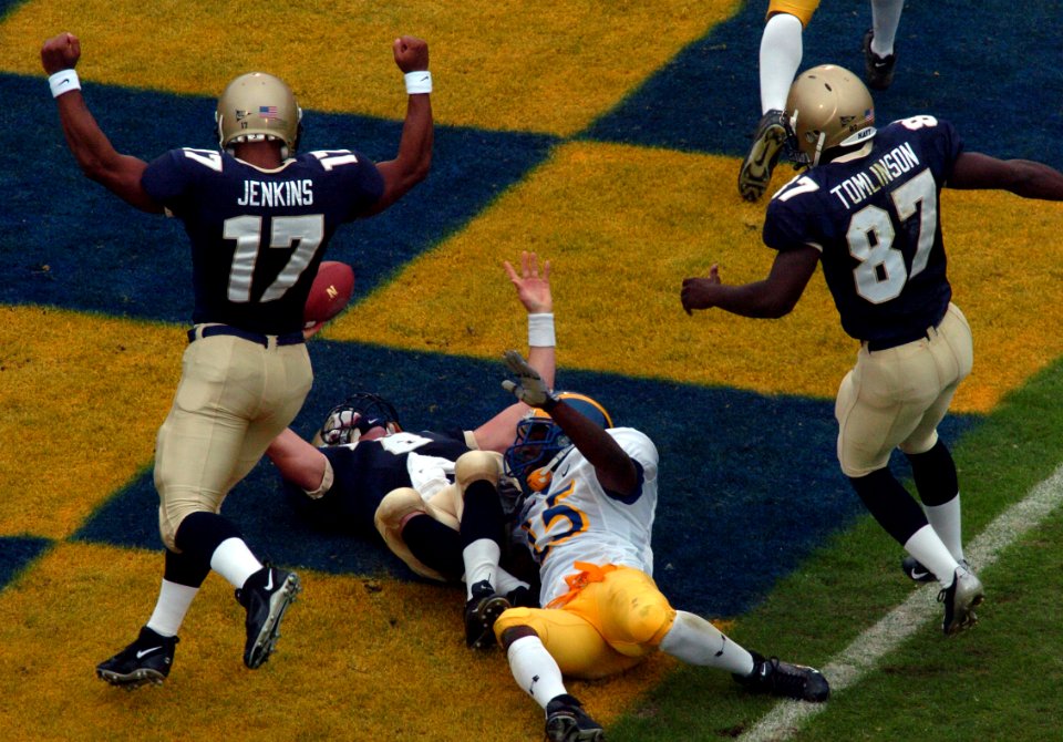 US Navy 041030-N-9693M-022 United States Naval Academy Midshipmen Amir Jenkins (17) and Jason Tomlinson (87) join Quarterback Aaron Polanco (6) in the endzone following Polanco's touchdown against the Delaware Blue Hens