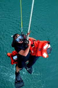 US Navy 041029-N-4772B-115 Search and rescue swimmer, Personnelman 3rd Class Gerardo A. Arbulu, gives the thumbs-up signal to be raised out of the water photo
