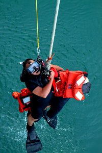 US Navy 041029-N-4772B-115 Search and rescue swimmer, Personnelman 3rd Class Gerardo A. Arbulu, gives the thumbs-up signal to be raised out of the water