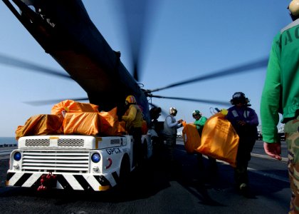 US Navy 041120-N-5345W-181 Crew members unload thousands of pounds of mail from the cargo hold of an A MH-53E Sea Dragon helicopter