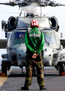US Navy 041230-N-4166B-015 The Enlisted Landing Signalman assigned to the Golden Falcons of Helicopter Anti-Submarine Squadron Two (HS-2), signals to the pilots of an HH-60H Seahawk helicopter on the flight deck of USS Abraham