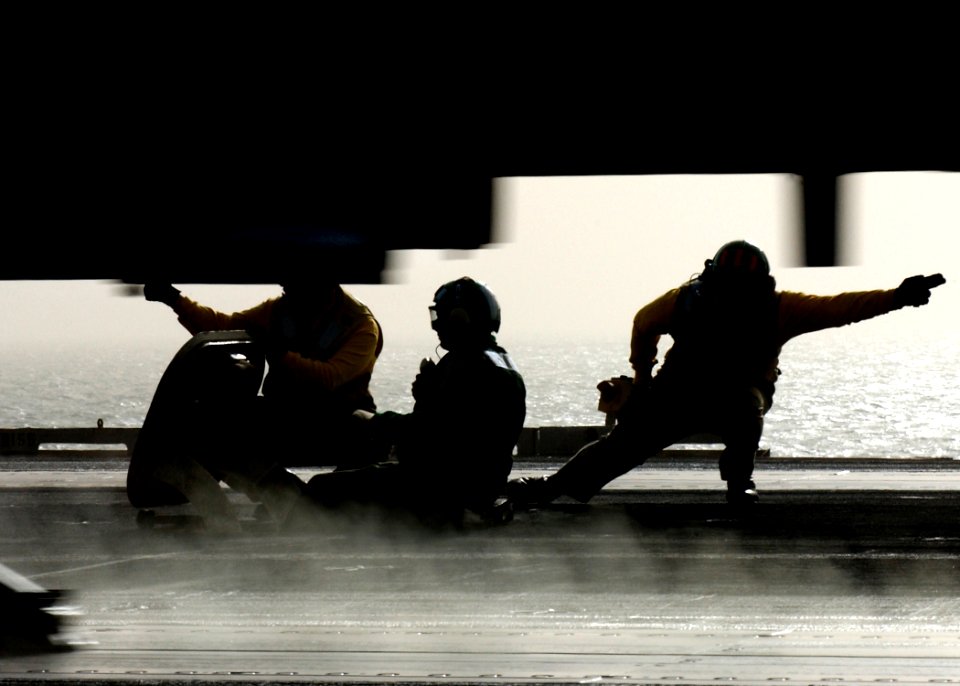 US Navy 041128-N-5345W-021 A catapult shooter holds his position while an F-A-18 Hornet launches past him and other flight deck personnel during flight operations aboard the Nimitz-class aircraft carrier USS Harry S. Truman (CV