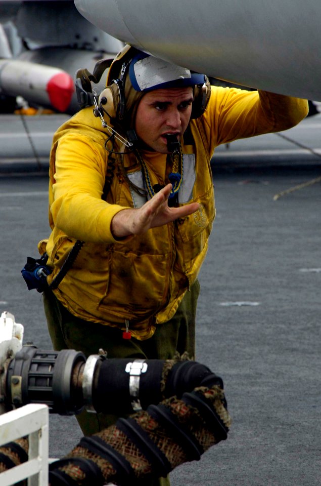 US Navy 041229-N-6074Y-137 An aircraft handler from USS Abraham Lincoln's (CVN 72) Air Department, uses hand signal to help guide an F-A-18 from Carrier Air Wing Two (CVW-2) onto an aircraft elevator aboard the ship