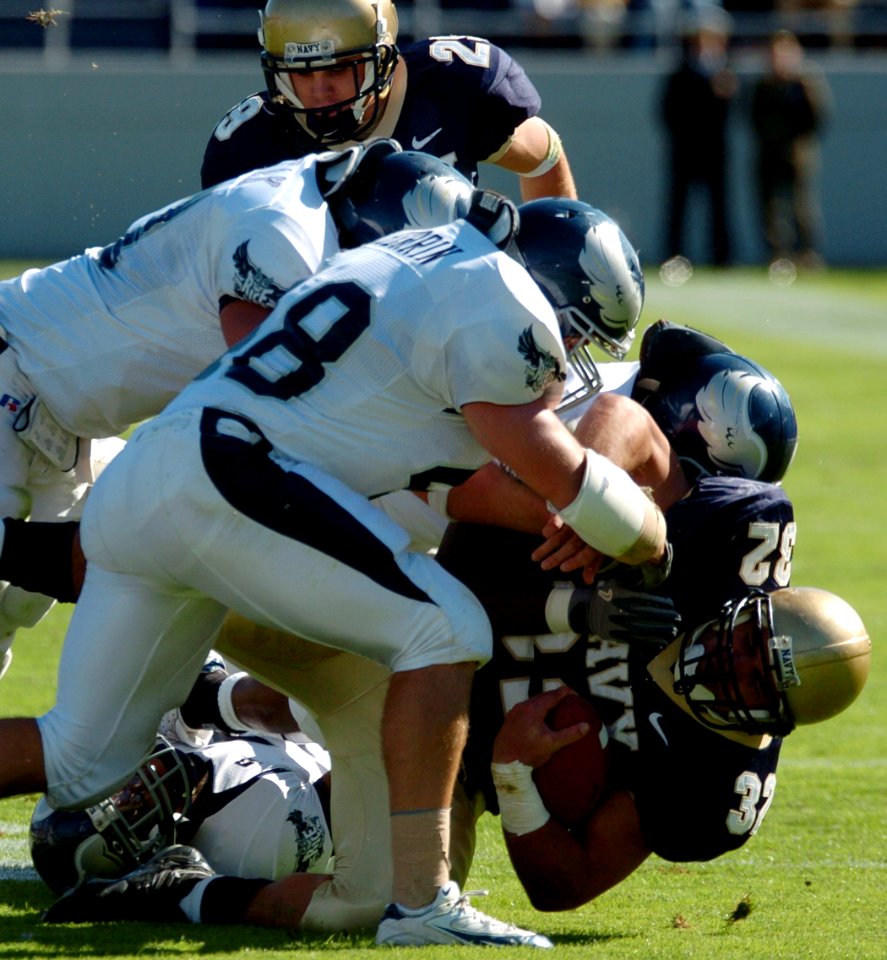 US Navy 041023-N-9693M-004 U.S. Naval Academy Midshipman 1st Class Kyle Eckel is tackled by Rice University defenders on a rushing attempt in the 1st quarter
