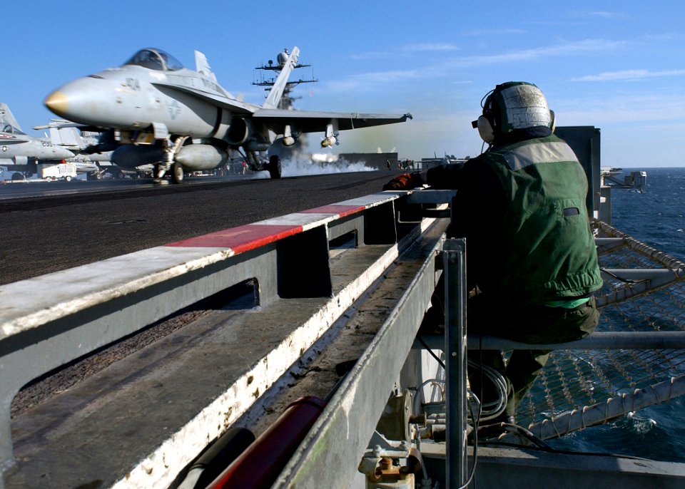 US Navy 041125-N-5345W-044 A bow safety watch stander observes an F-A-18C assigned to the Gunslingers of Strike Fighter Squadron One Zero Five (VFA-105), launched off the flight deck aboard the Nimitz-class aircraft carrier USS