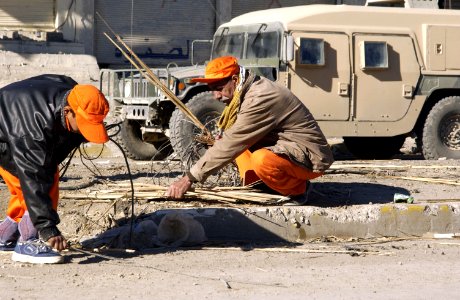 US Navy 041213-N-4614W-002 An Iraqi man joins twenty-one other contracted nationals to clear debris from a major thoroughfare in Fallujah, Iraq photo