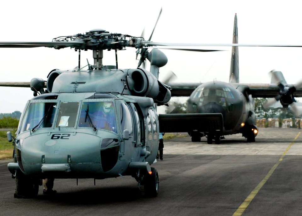 US Navy 050103-N-4166B-210 An MH-60S Knighthawk helicopter and an Australian C-130 Hercules cargo aircraft prepare for takeoff at the Sultan Iskandar Muda Air Force Base in Aceh, Sumatra, Indonesia