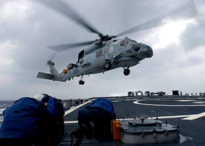 US Navy 050103-N-9079D-256 Sailors keep covered as an SH-60B Seahawk, assigned to the Saberhawks of Helicopter Anti-Submarine Squadron Light Four Seven (HSL-47), lands aboard the guided missile destroyer USS Benfold (DDG 65)