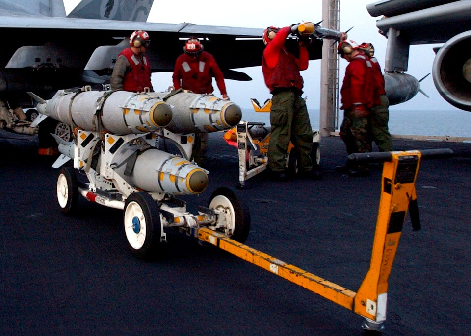 US Navy 041220-N-6363M-018 Aviation Ordnancemen assigned to the Gunslingers of Strike Fighter Squadron One Zero Five (VFA-105), pull a skid loaded with three GBU-38 500 pound satellite guided bombs