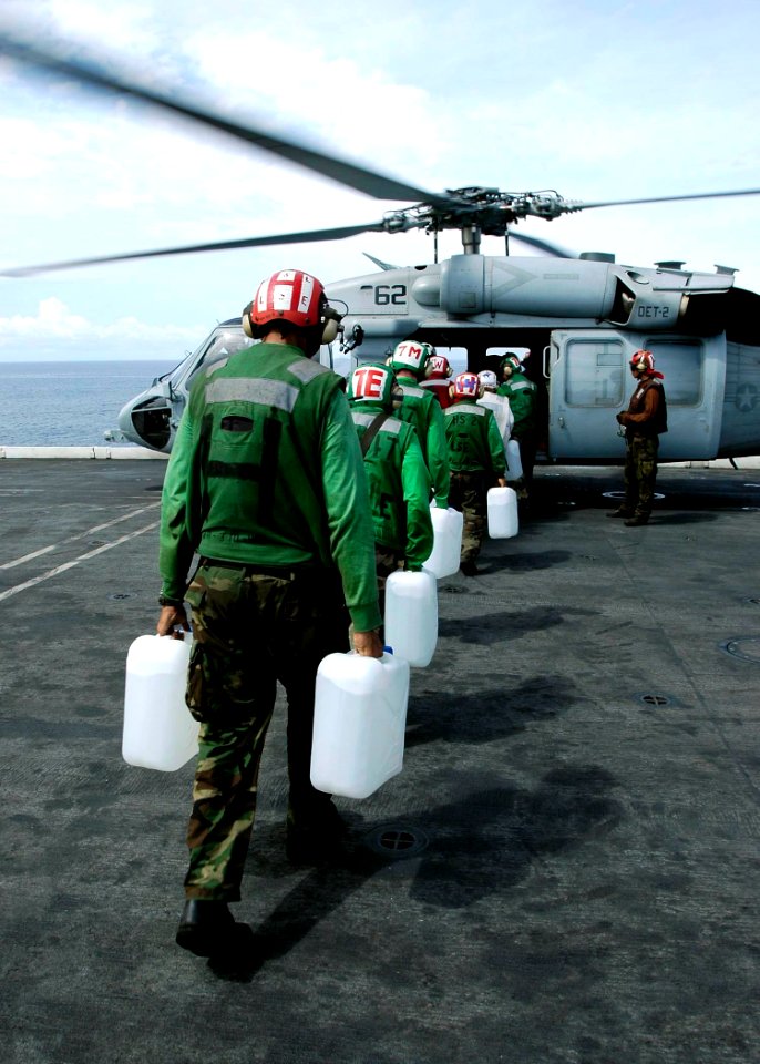US Navy 050105-N-4166B-096 Sailor's aboard USS Abraham Lincoln (CVN 72) load jugs of purified water on board an awaiting MH-60S Knighthawk helicopter