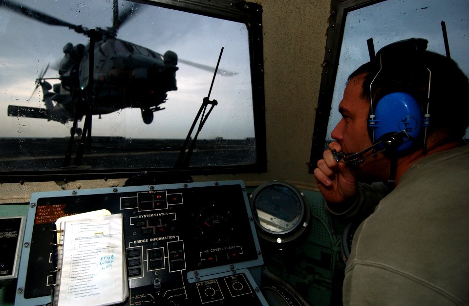 US Navy 050110-N-6932B-026 Lt. Cmdr. Roger Hartman, officer in charge of the Grandmasters of Helicopter Antisubmarine Squadron Light Four Six (HSL-46) detachment 4, directs an SH-60B Seahawk in for landing aboard