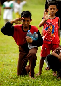 US Navy 050106-N-4166B-488 A lone hand salute is rendered by an Indonesian child as a U.S. Navy helicopter lifts off after delivering food and water in Lamno, Sumatra, Indonesia photo