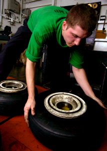 US Navy 041220-N-5837R-033 Aviation Structural Mechanic Airman Anthony Edwards prepares to bead a nose mount tire for an F-A-18 Hornet