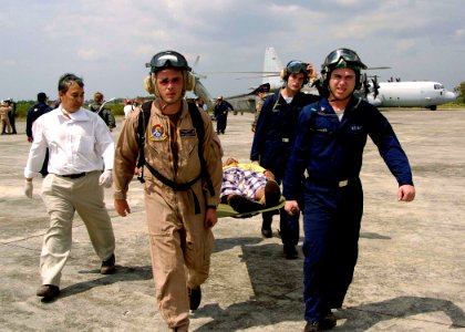 US Navy 050103-N-0057P-462 Sailors assigned to USS Abraham Lincoln (CVN 72) and embarked Carrier Air Wing Two (CVW-2), carry a refugee off an SH-60B Seahawk en route to the U.S. Medical tent for treatment in Aceh, Sumatra, Indo