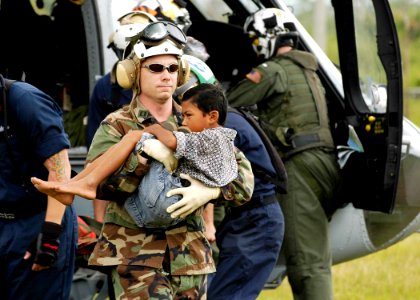 US Navy 050106-N-4166B-282 Lt. Shawn Harris, assigned to the guided missile destroyer USS Shoup (DDG 86), carries an injured boy from an MH-60S Knighthawk helicopter to a triage site