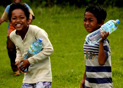 US Navy 050109-N-4166B-141 Indonesian children smile as they receive much-needed bottles of water flown-in by a Navy Seahawk helicopter