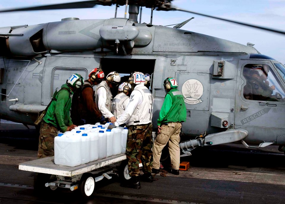 US Navy 050105-N-4166B-052 Sailor's aboard USS Abraham Lincoln (CVN 72) load jugs of purified water on board an awaiting HH-60H Seahawk helicopter