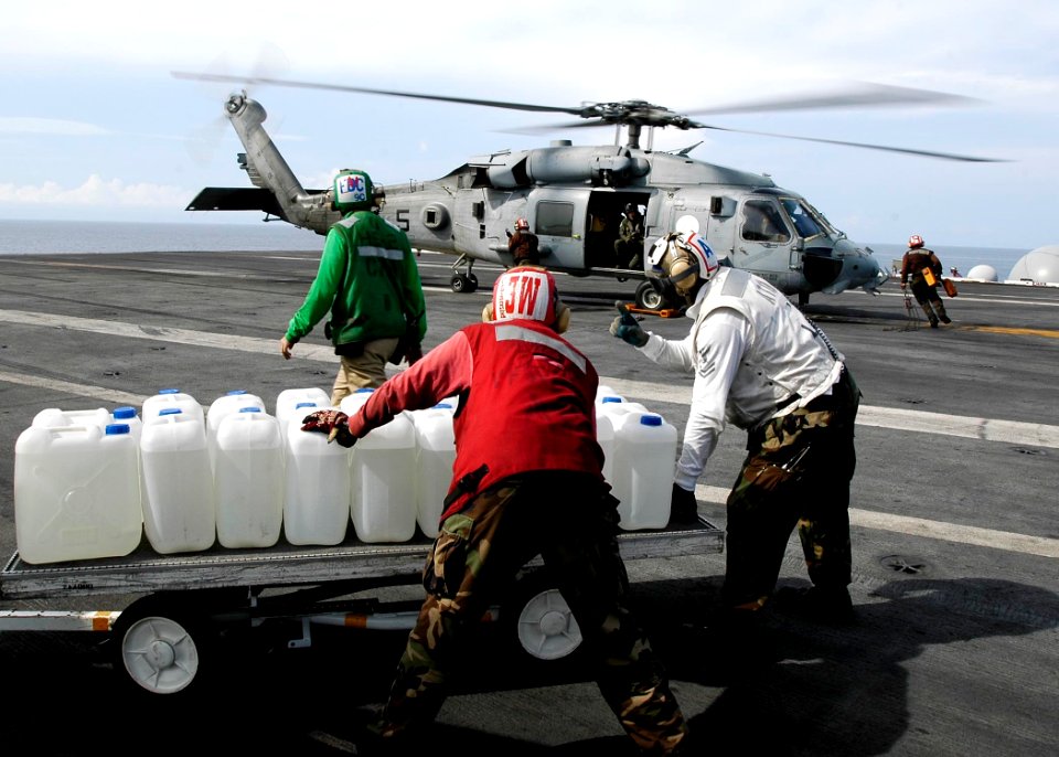 US Navy 050105-N-4166B-012 Sailor's aboard USS Abraham Lincoln (CVN 72) prepare to load jugs of purified water on board an awaiting HH-60H Seahawk helicopter