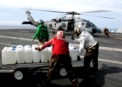 US Navy 050105-N-4166B-012 Sailor's aboard USS Abraham Lincoln (CVN 72) prepare to load jugs of purified water on board an awaiting HH-60H Seahawk helicopter