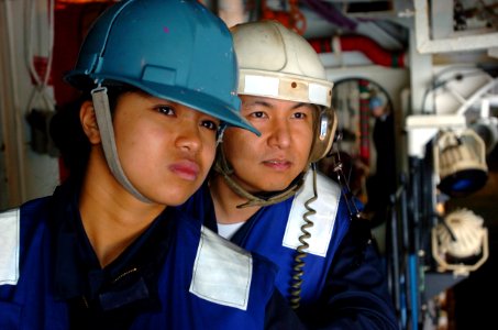US Navy 050126-N-9866B-011 Seaman Caroline Castillo, front, and Boatswain's Mate 2nd Class Desi Bautista look over the well deck just before a landing craft utility pulled inside the amphibious assault ship USS Peleliu (LHA 5)