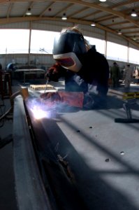US Navy 050204-A-0000C-001 Hull Technician 3rd Class Jessica Curtis, welds side-panel armor for a U.S. Army 5-ton truck at Camp Buehring, Kuwait
