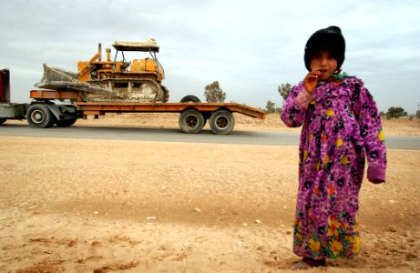 US Navy 050124-N-1810F-598 An Iraqi local girl walks away from the side of a road where she received a lollipop by a passing American convoy