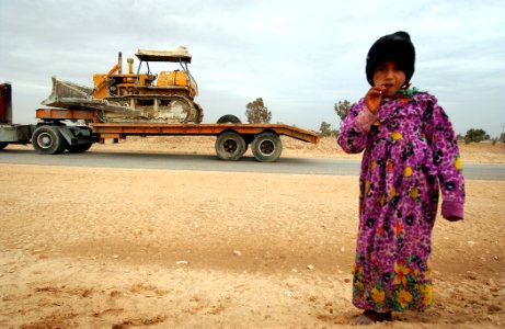 US Navy 050124-N-1810F-598 An Iraqi local girl walks away from the side of a road where she received a lollipop by a passing American convoy photo