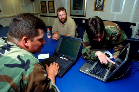 US Navy 050123-N-2653P-001 Officer-in-Charge of Navy Oceanographic Office Fleet Survey Team One and Two, Lt. Cmdr. Todd Barnhill, left, compares data with teammates Lt. Deborah Mabey, right, and Forrest Noll, aboard the guided
