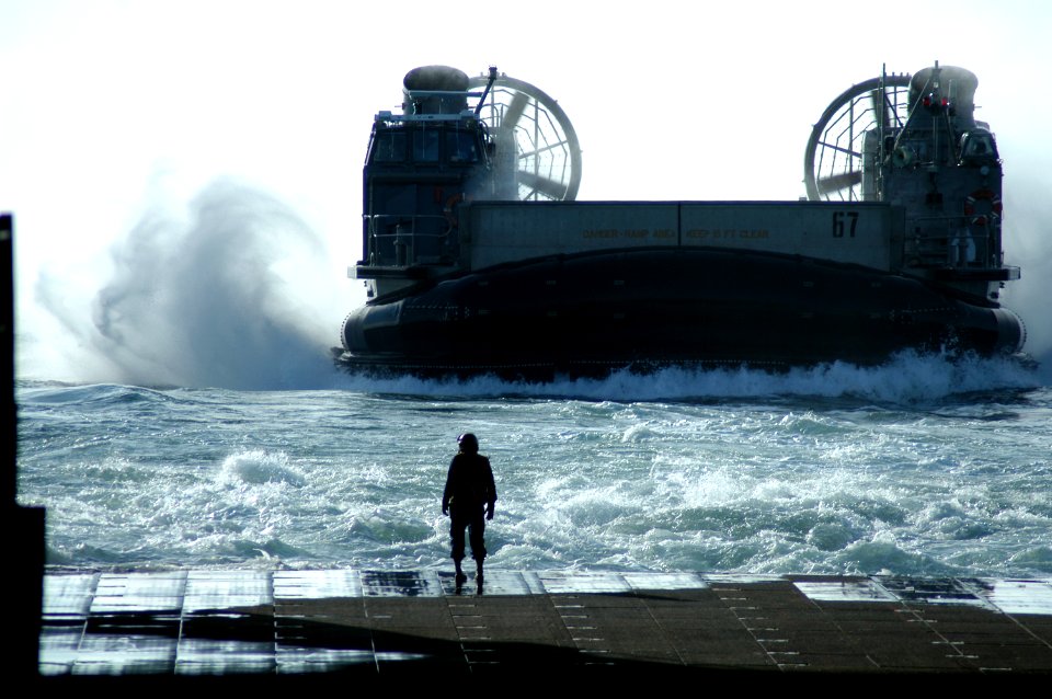 US Navy 050125-N-8154G-032 Boatswain's Mate 3rd Class Tony Layton watches as a Landing Craft Air Cushion (LCAC), assigned to Assault Craft Unit Four (ACU-4), prepares to enter the well deck of the amphibious assault ship