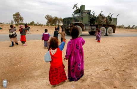 US Navy 050124-N-1810F-617 Iraqi children wave to an American convoy that passes on a local road photo