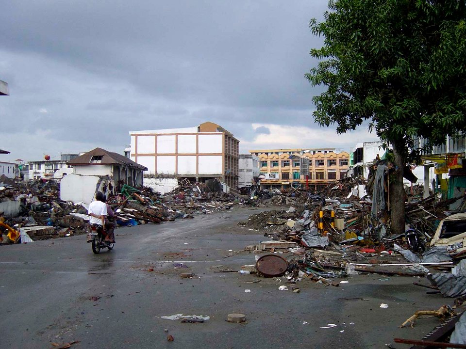 US Navy 050101-O-XXXXB-072 Trash and debris line the streets while locals check on the aftermath in down town Aceh, Sumatra following a massive Tsunami that struck the area on the 26th of December 2004