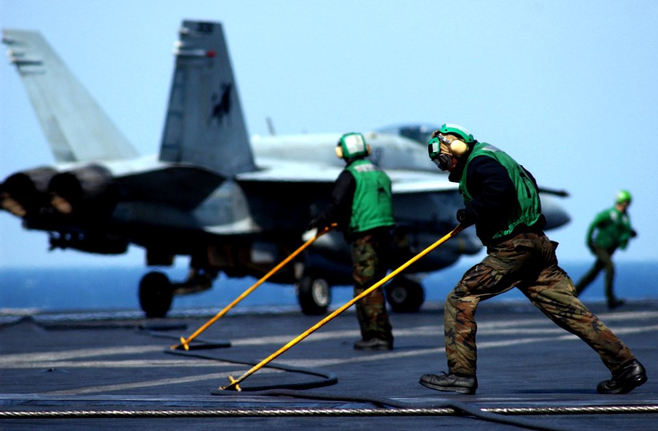 US Navy 050212-N-6363M-051 Sailors assigned to the Air Department aboard USS Harry S. Truman (CVN 75) use push bars to guide the arresting wire back into position after recovering an F-A-18C Hornet