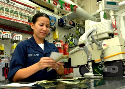 US Navy 050103-N-9079D-020 Seaman Jaimee Lorenzo counts money while working as a clerk in the ship store aboard the guided missile destroyer USS Benfold (DDG 65)