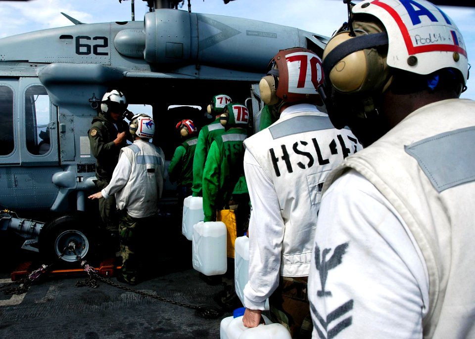 US Navy 050105-N-4166B-099 Sailor's aboard USS Abraham Lincoln (CVN 72) load jugs of purified water on board an awaiting MH-60S Knighthawk helicopter