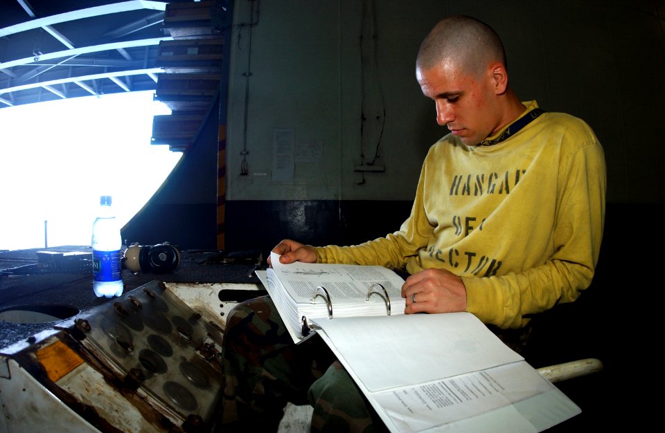 US Navy 050302-N-0380T-010 Airman Bradey Jones of Sioux Falls, S. D., takes time during a break in operations to study for his upcoming advancement exam in the hangar bay aboard the Nimitz-class aircraft carrier USS Carl Vinson