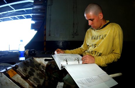 US Navy 050302-N-0380T-010 Airman Bradey Jones of Sioux Falls, S. D., takes time during a break in operations to study for his upcoming advancement exam in the hangar bay aboard the Nimitz-class aircraft carrier USS Carl Vinson