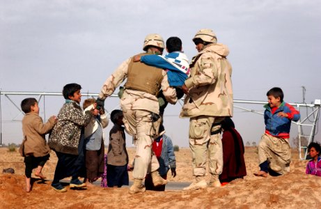US Navy 050124-N-1810F-487 Ens. Majid Awad from Bahrain, assist a local Iraqi child photo