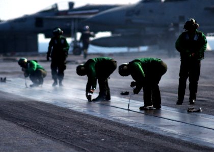 US Navy 050208-N-6363M-005 Air Department personnel place buttons in the slot of catapult number three in preparation for arrested landings on the flight deck